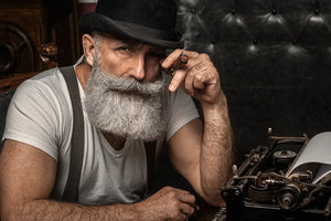 Old man smoking a cigar indoors. Mafia concept. Stylish male in his cabinet. Bearded man.