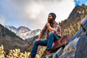 happy bearded guy sitting on luggage at top 