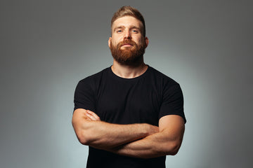 young man wearing black shirt with red hair and beard arms crossed